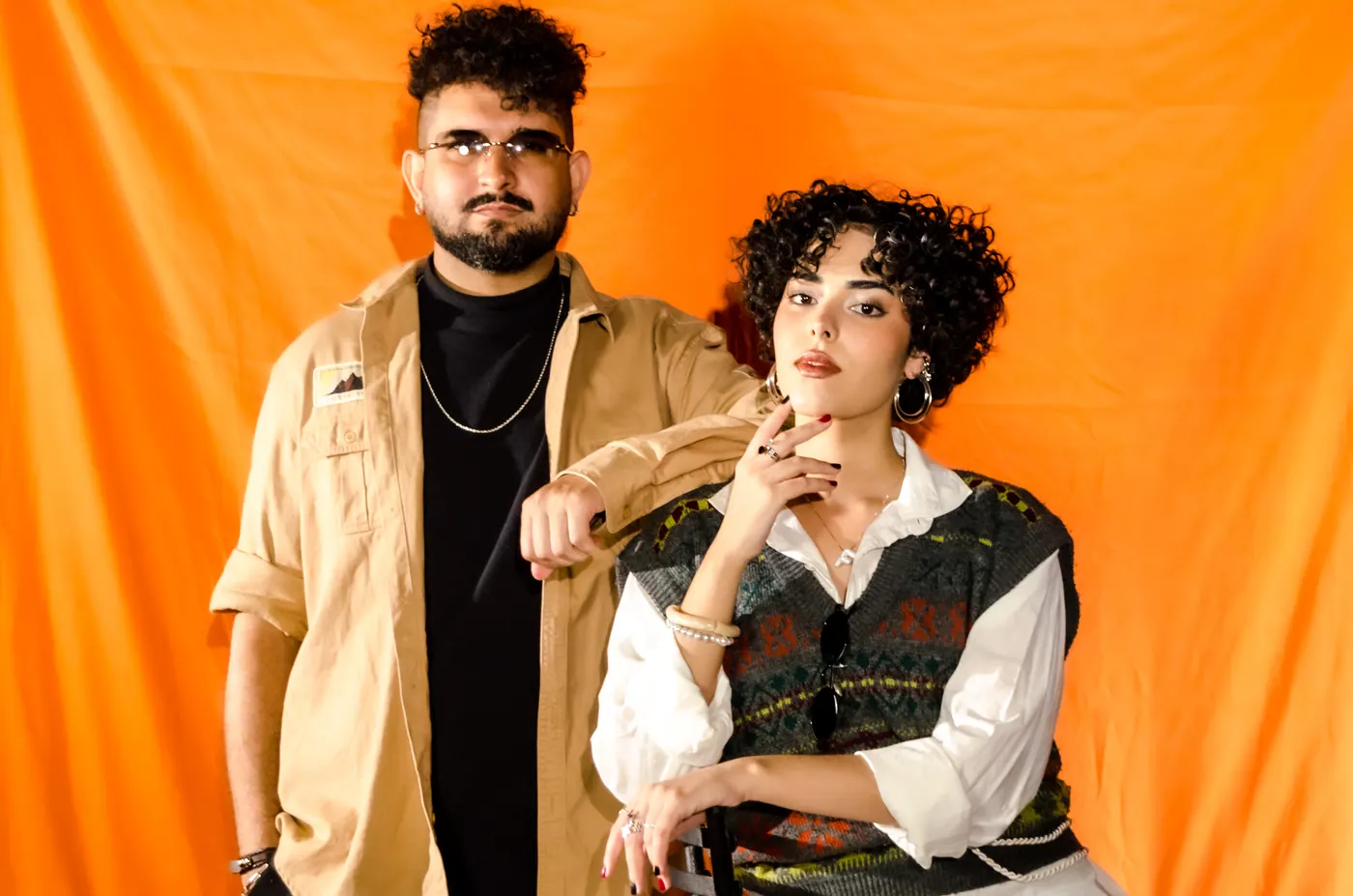 Elias em pé e Flavy sentada à frente, olhando para o lado